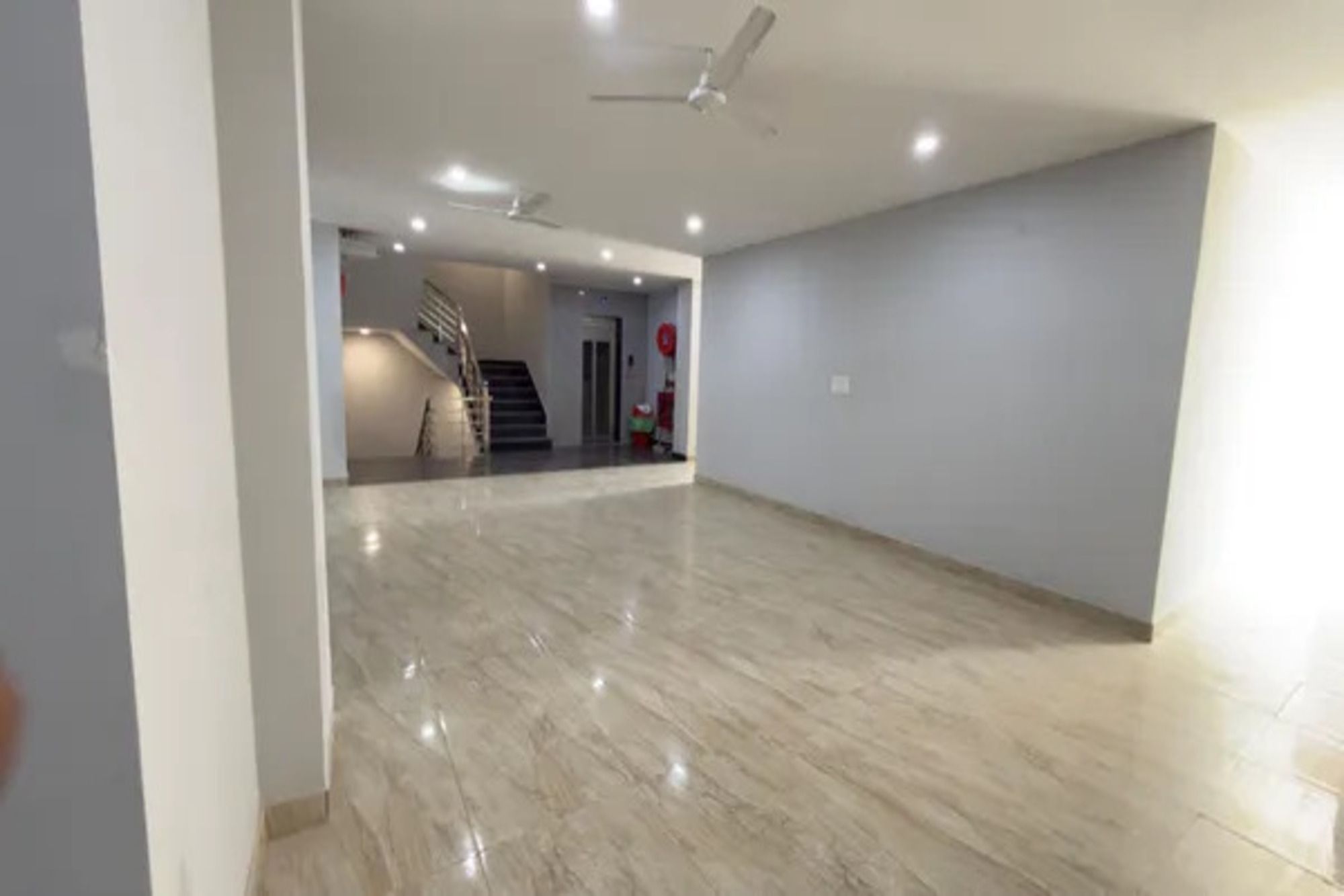 Una habitación amplia con piso de mármol, ventilador de techo e iluminación empotrada.