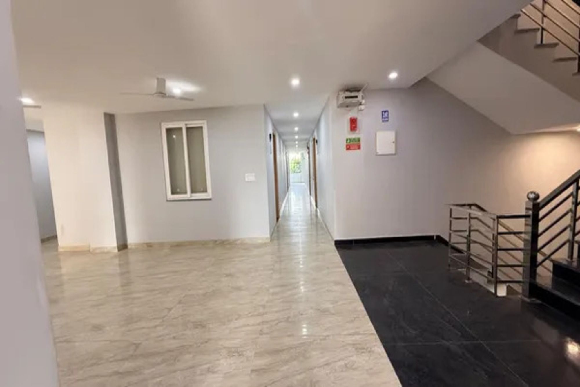 A corridor with a ceiling fan, a window, and a staircase.