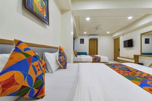 Una habitación de hotel con una cama grande, un televisor y una puerta que da a otra habitación.