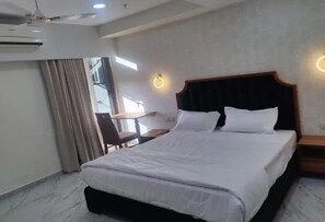 A hotel room with a bed, a desk, and a chair. - FabHotel Januson (Gandhinagar)