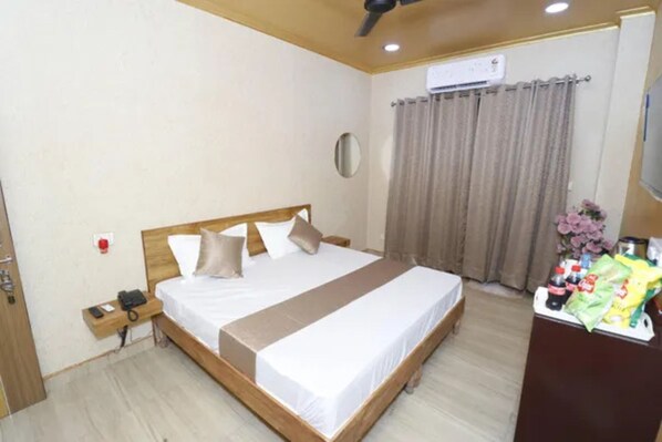 Habitació d'hotel amb llit, taula de nit i escriptori petit amb productes de tocador.