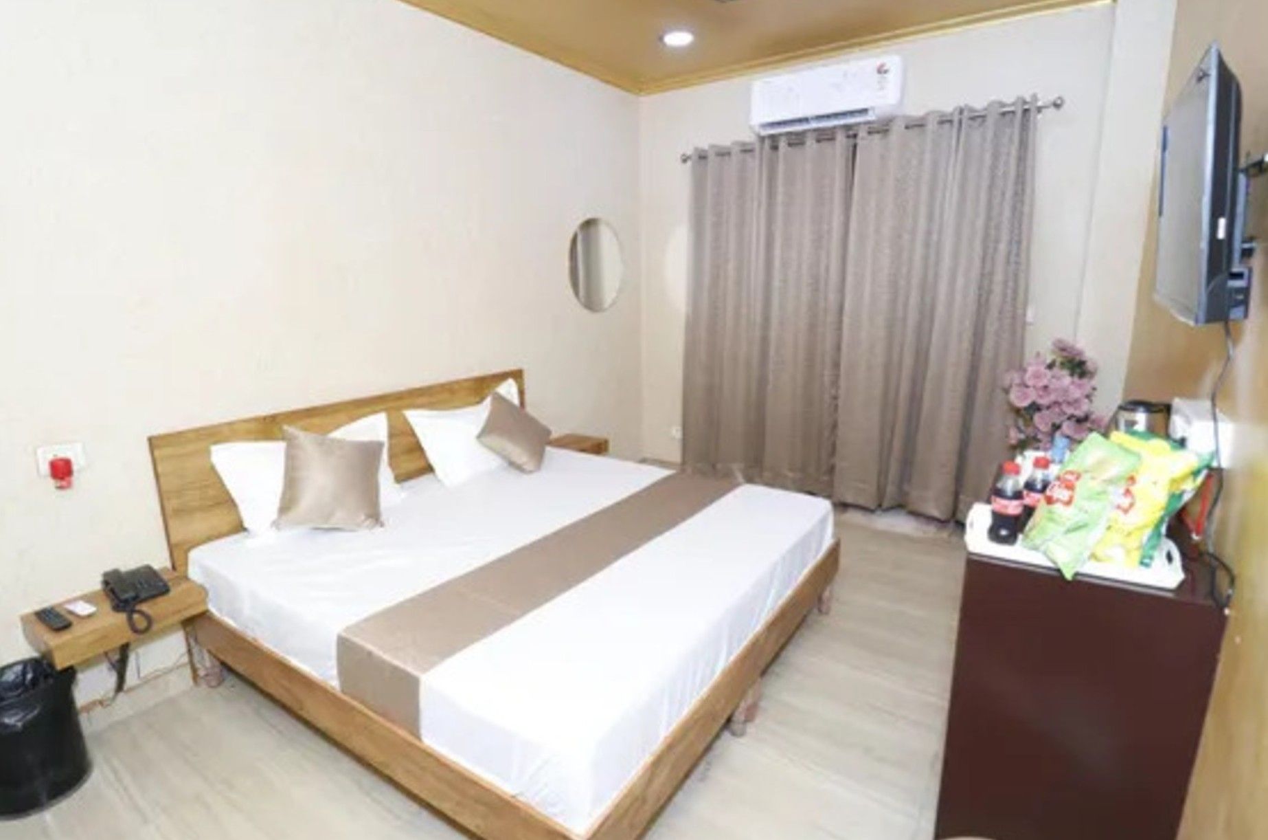 Una habitación de hotel con cama, mesita de noche y televisor.