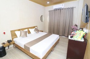 A hotel room with a bed, bedside table, and a TV. - FabHotel Skyline Residency (Ghaziabad)