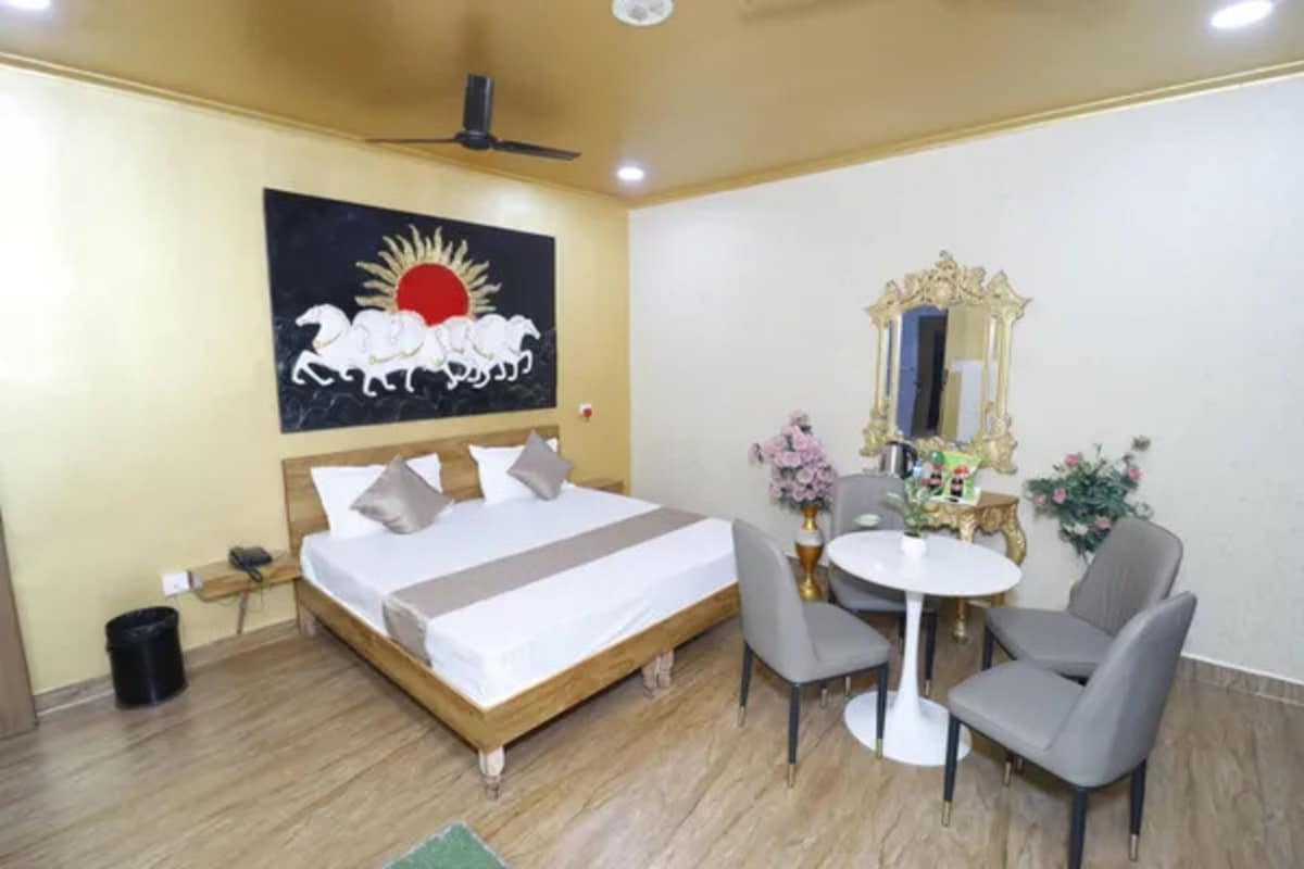 A hotel room with a bed, a round table, and two chairs.