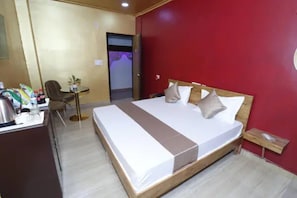 Una habitación de hotel con una cama, un escritorio, una silla y una mesita.