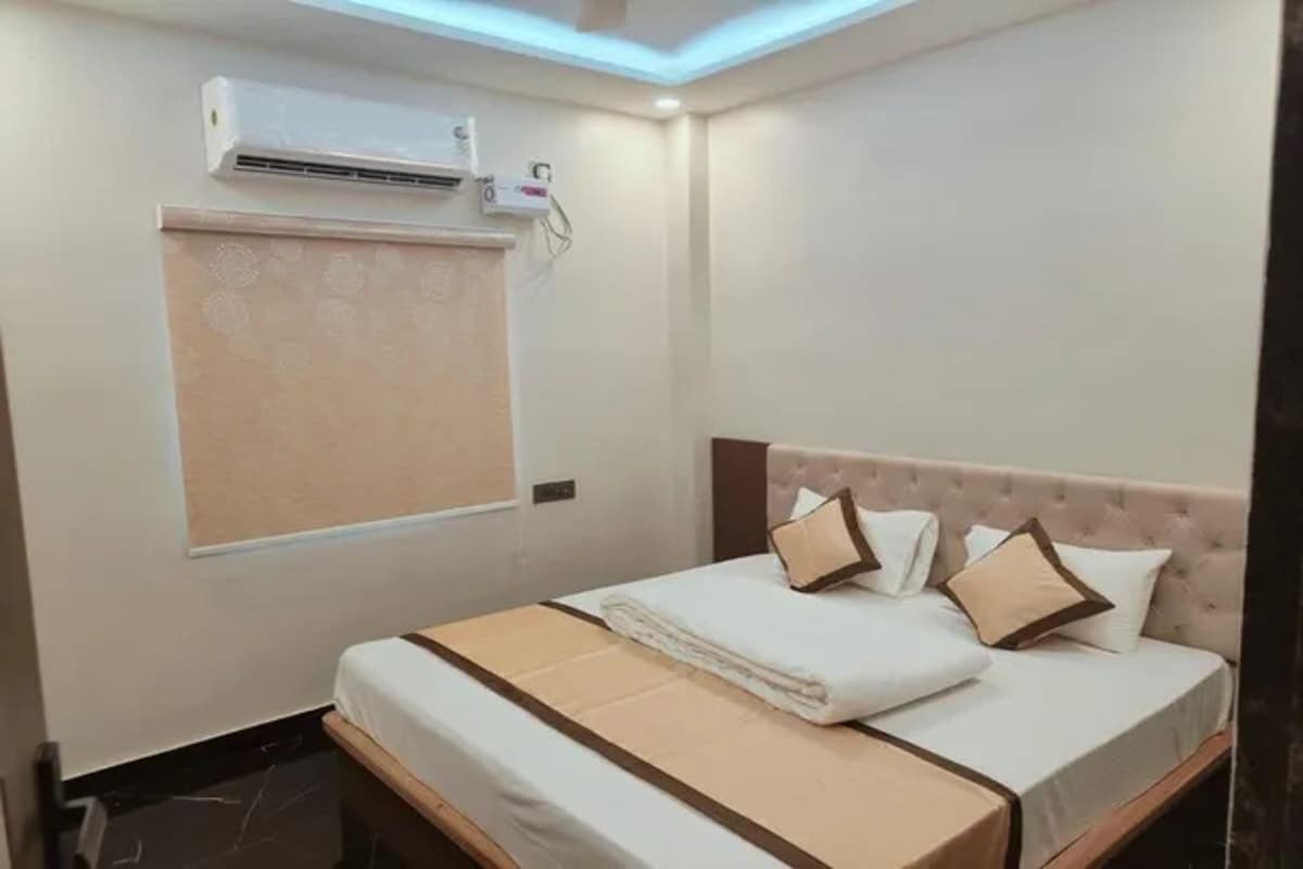 Een hotelkamer met een bed, een raam met zonwering, een airconditioning en een plafondlamp.