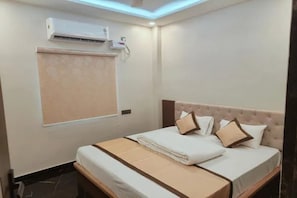 Een hotelkamer met een bed, een raam met zonwering, een airconditioning en een plafondlamp.
