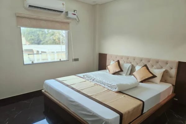 Een hotelkamer met een bed, een raam, een airconditioning en een apparaat aan de muur.