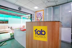 Una recepción con un cartel de 'fab hotels', un reloj y una ventana con vistas al exterior.