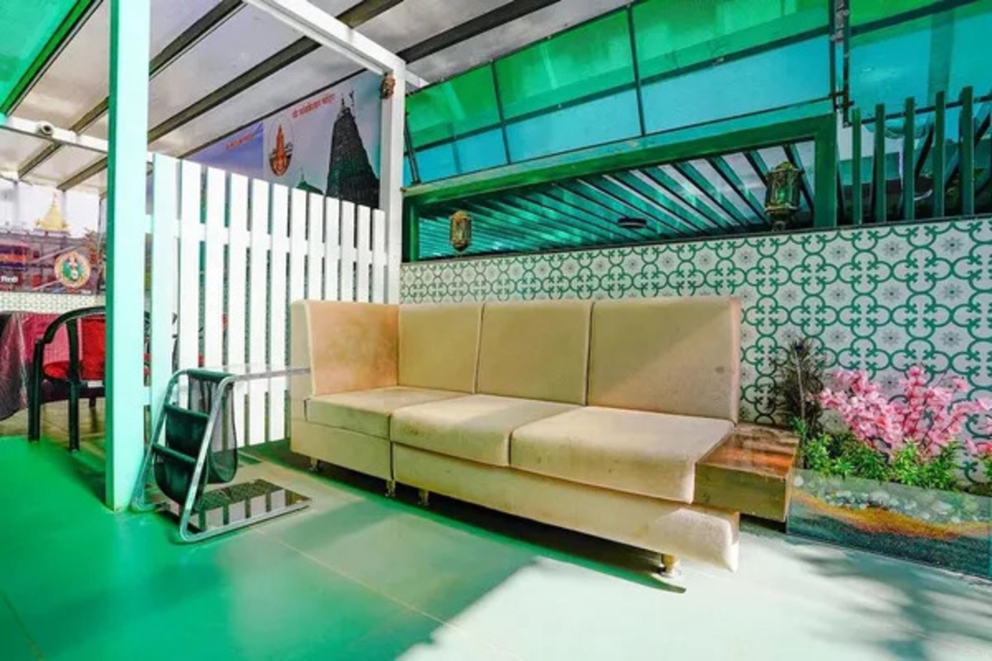 A room with a beige sofa, a green floor, a patterned wall, and a window with a view.