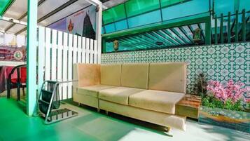A room with a beige sofa, a green floor, a patterned wall, and a window with a view.
