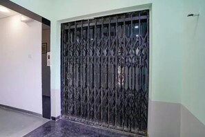 Una habitación con una reja metálica oscura, una pared de tono claro y suelo de baldosas.