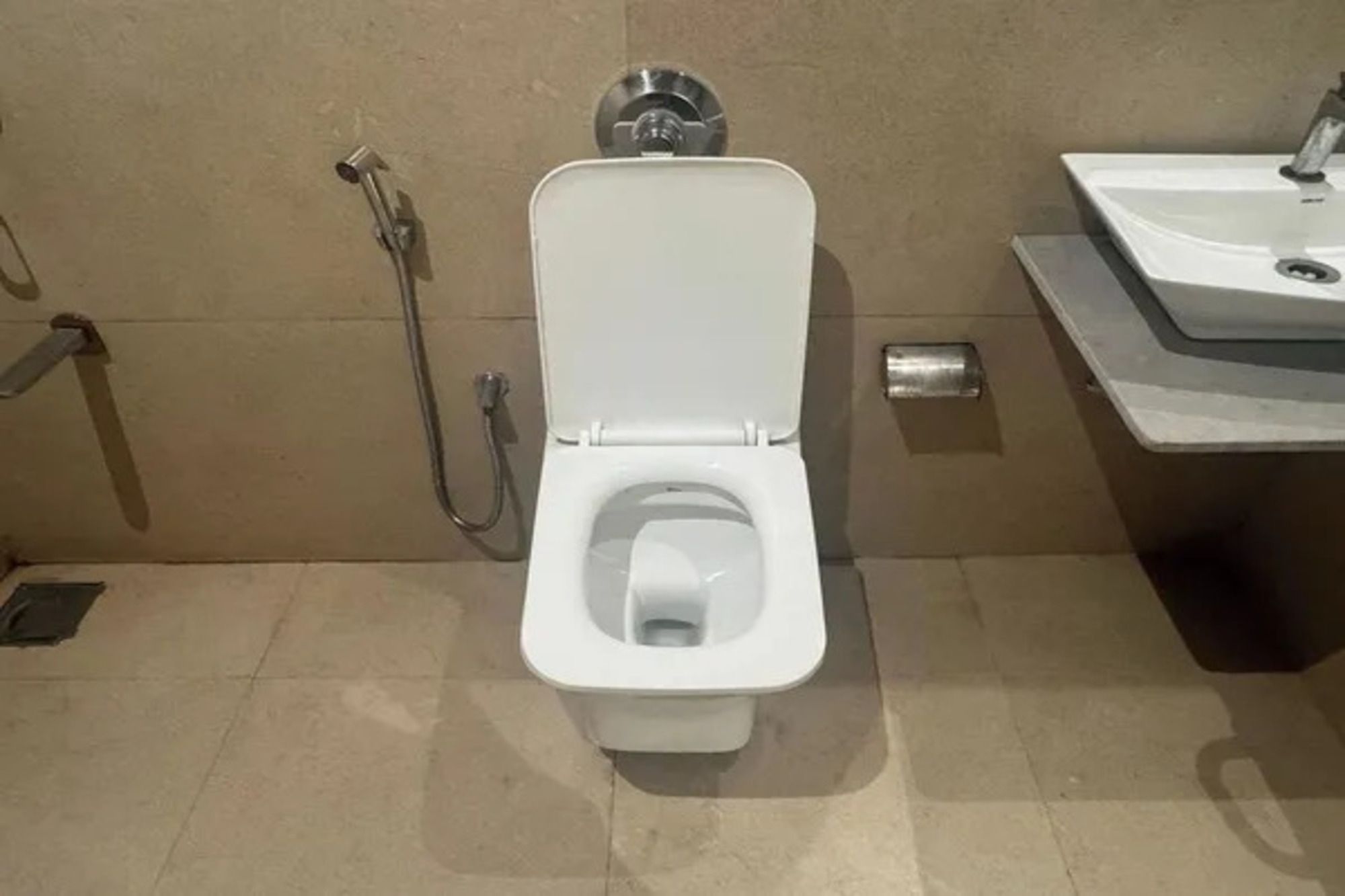 Inodoro con bidé incorporado, lavamanos y ducha en un baño.