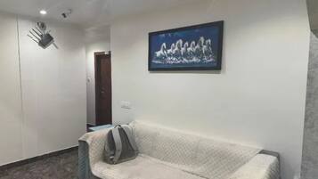 Una habitación con un sofá, un cuadro en la pared y una puerta al fondo.