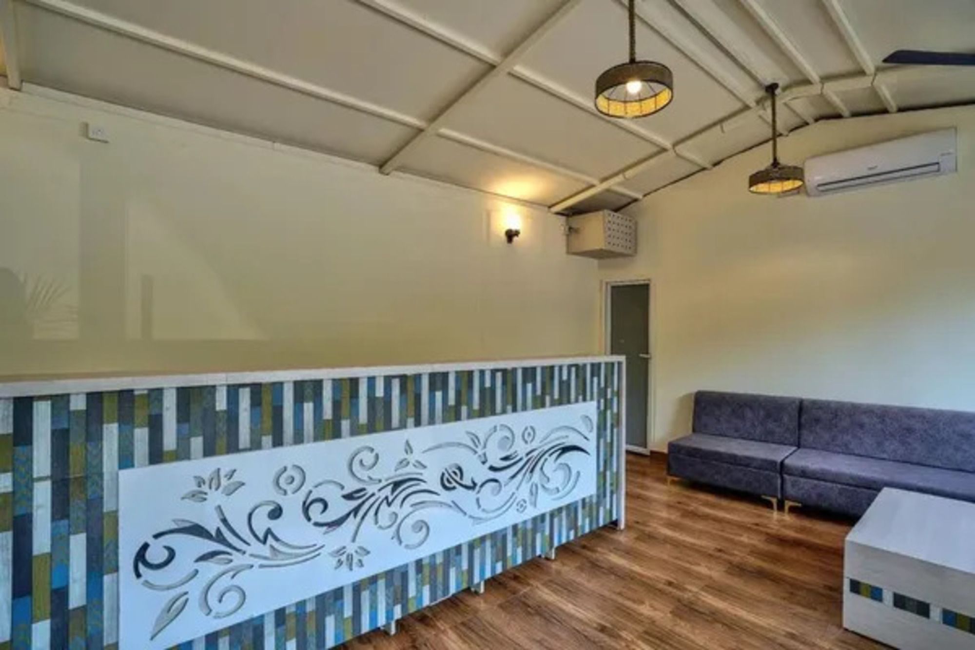 A reception area with a patterned counter, a sofa, and a ceiling with exposed beams and hanging lights.