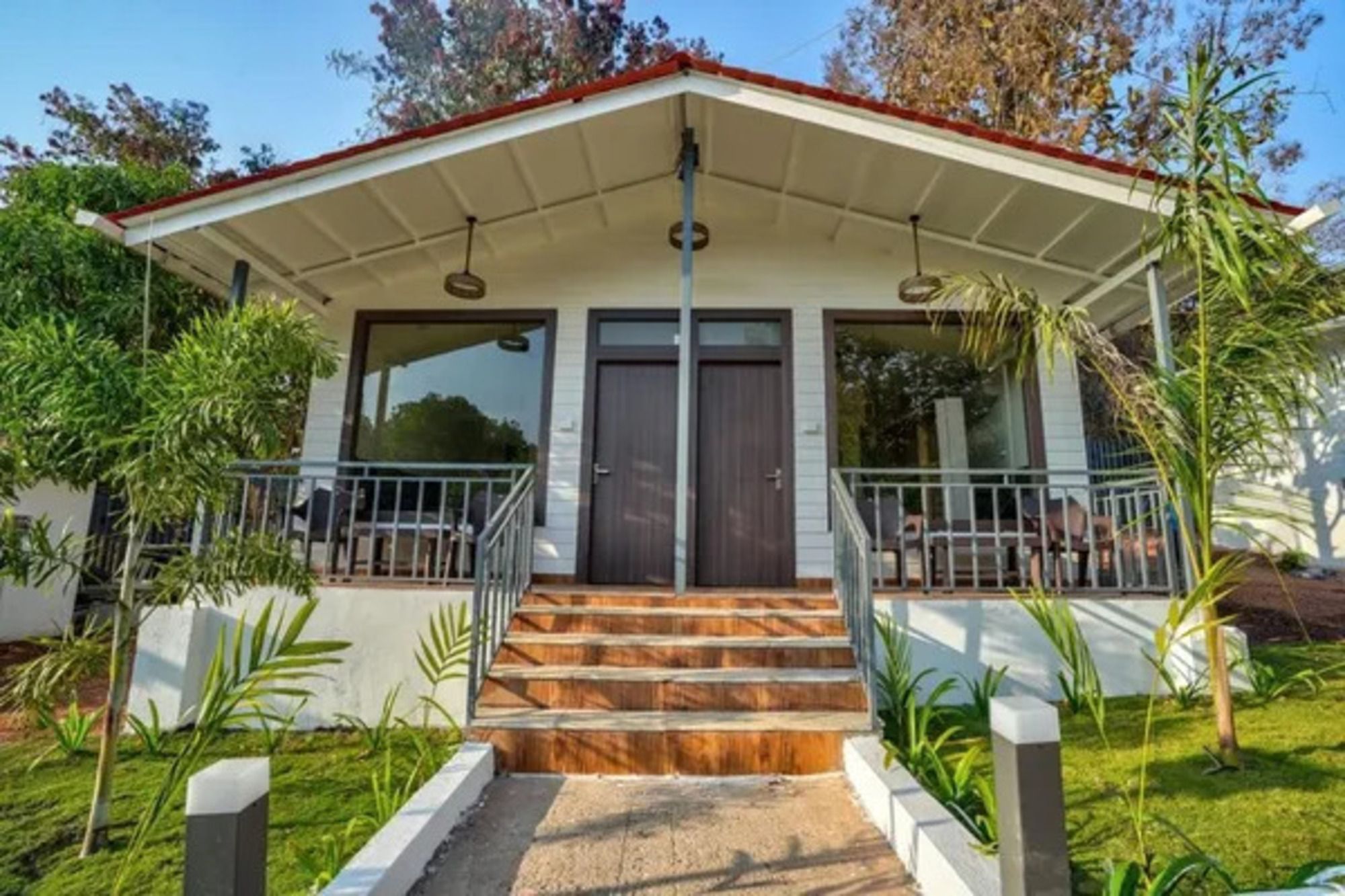 A two-story building with a covered porch, a staircase leading to the entrance, and a small outdoor seating area.