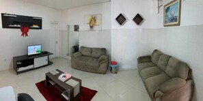 Ein Wohnzimmer mit Flachbildfernseher, zwei Sofas, einem Couchtisch und einem roten Teppich.