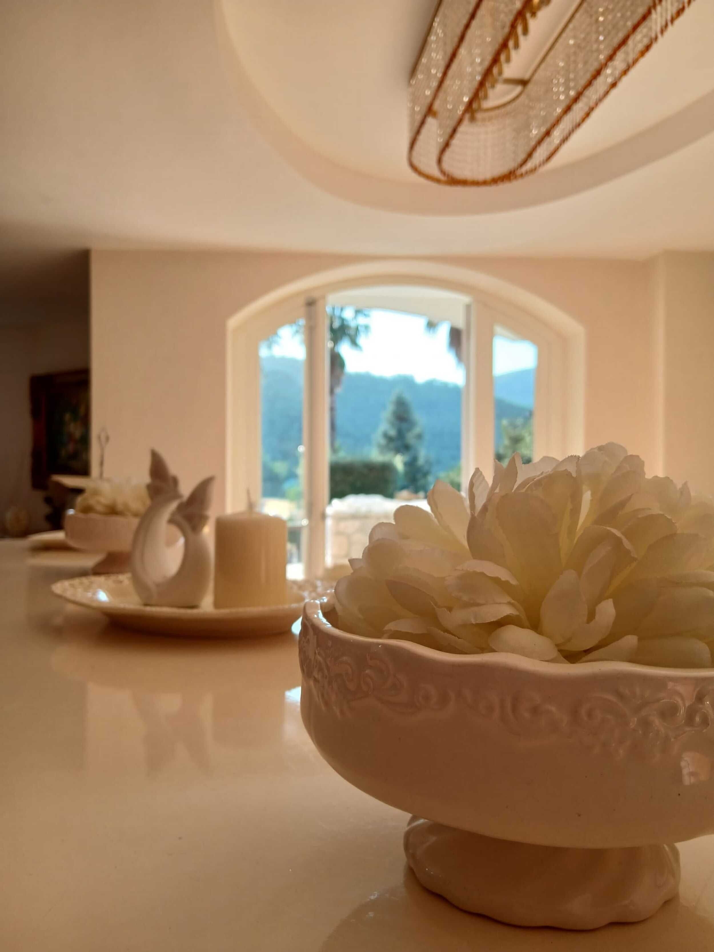 Un coin repas avec une table dressée pour deux personnes, agrémenté d’un bol en céramique blanche orné de motifs floraux et d’une tasse en céramique blanche.