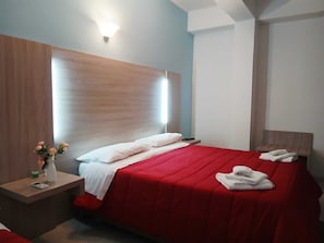 Ein Hotelzimmer mit Bett, Nachttisch, einer Blumenvase und einer Wandleuchte.