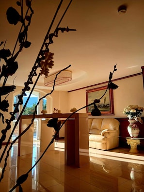 Ein geräumiges Wohnzimmer mit einer Ledersofa, einem Chandelier und einem großen Gemälde an der Wand.