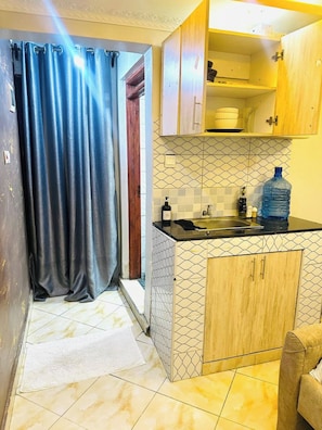 A kitchen with a sink, cabinets, and a water dispenser. - Lulu Nest studio Umoja (Nairobi)