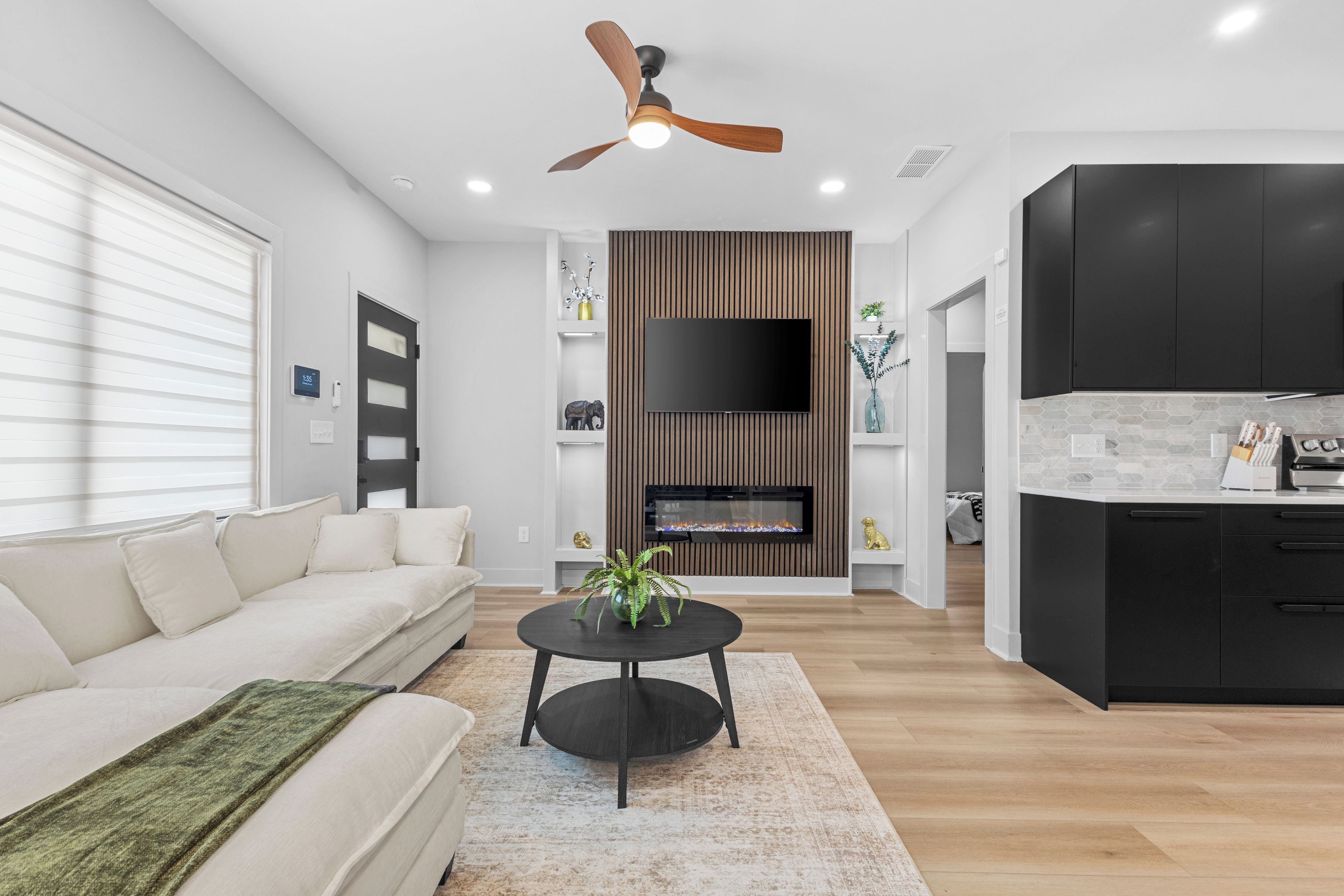 A modern living room with a sofa, coffee table, and a flat-screen TV mounted on a wooden wall.