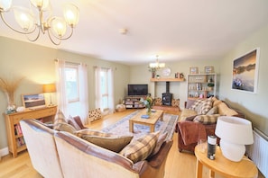 A cozy living room with a sofa set, a coffee table, a TV, a fireplace, and a bookshelf.