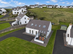 A residential area with houses, a driveway, and a grassy hill.