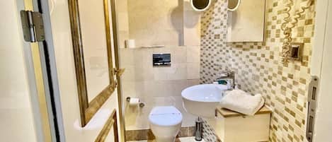 A bathroom with a toilet, sink, and shower area.