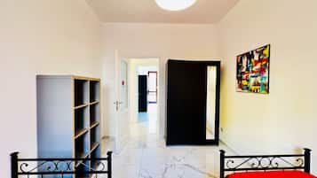 Una camera d'albergo con un letto, un armadio, una porta che dà su un'altra stanza e un quadro appeso al muro.