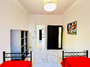 Habitación de hotel con cama, armario, puerta que da a otra habitación y un cuadro en la pared.