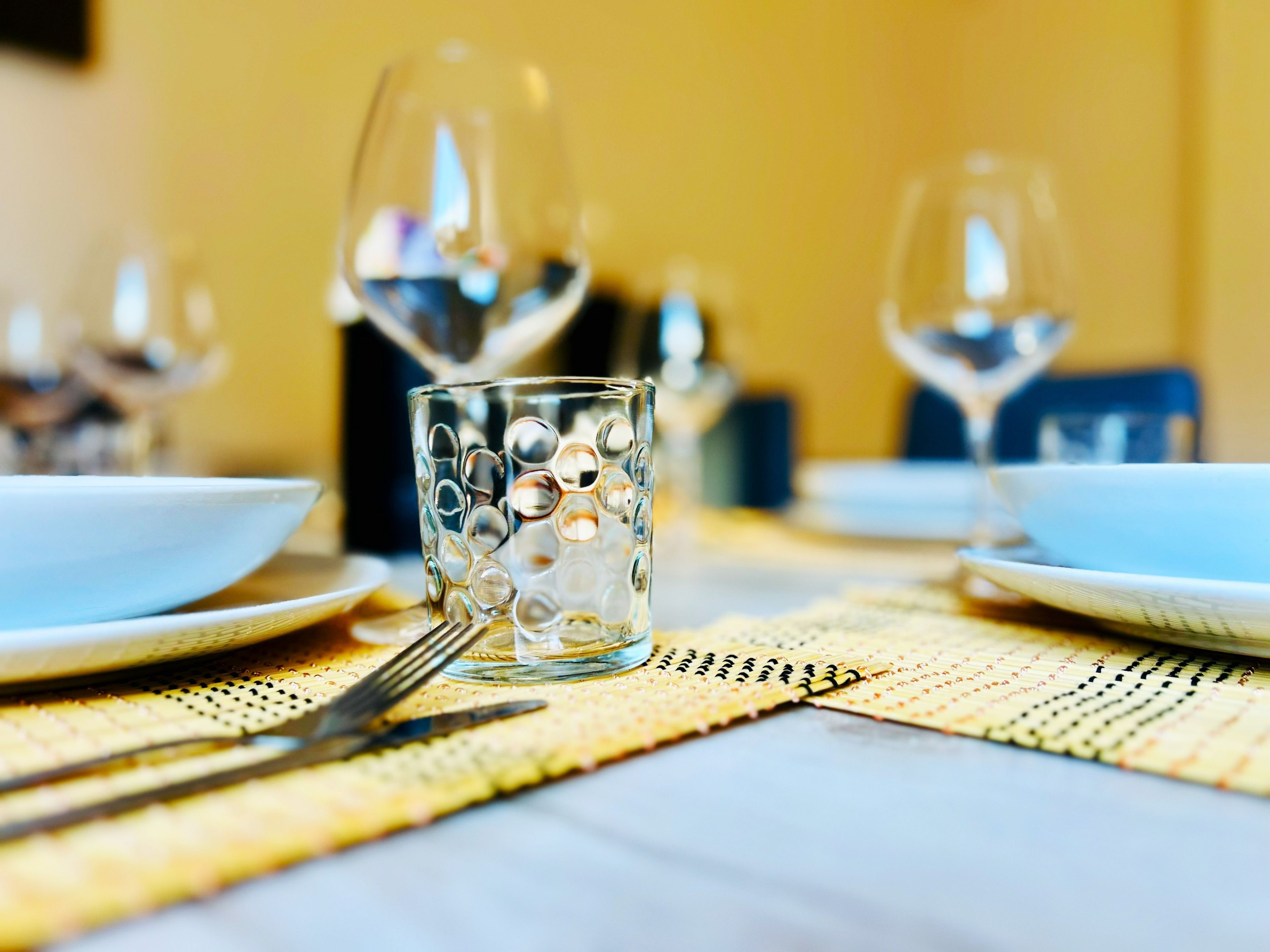 Une table à manger avec des assiettes, des couverts et des verres, ce qui laisse supposer qu’un repas va être servi.