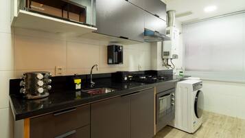 A modern kitchen with a built-in oven, a microwave, a sink, and a washing machine.