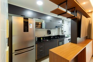 A modern kitchen with a stainless steel refrigerator, a built-in oven, a black countertop, and wooden cabinetry. - New Listing (Rio de Janeiro)