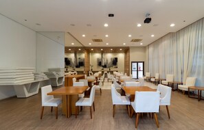A spacious dining area with multiple tables and chairs, a large window with curtains, and a modern ceiling design. - New Listing (Rio de Janeiro)