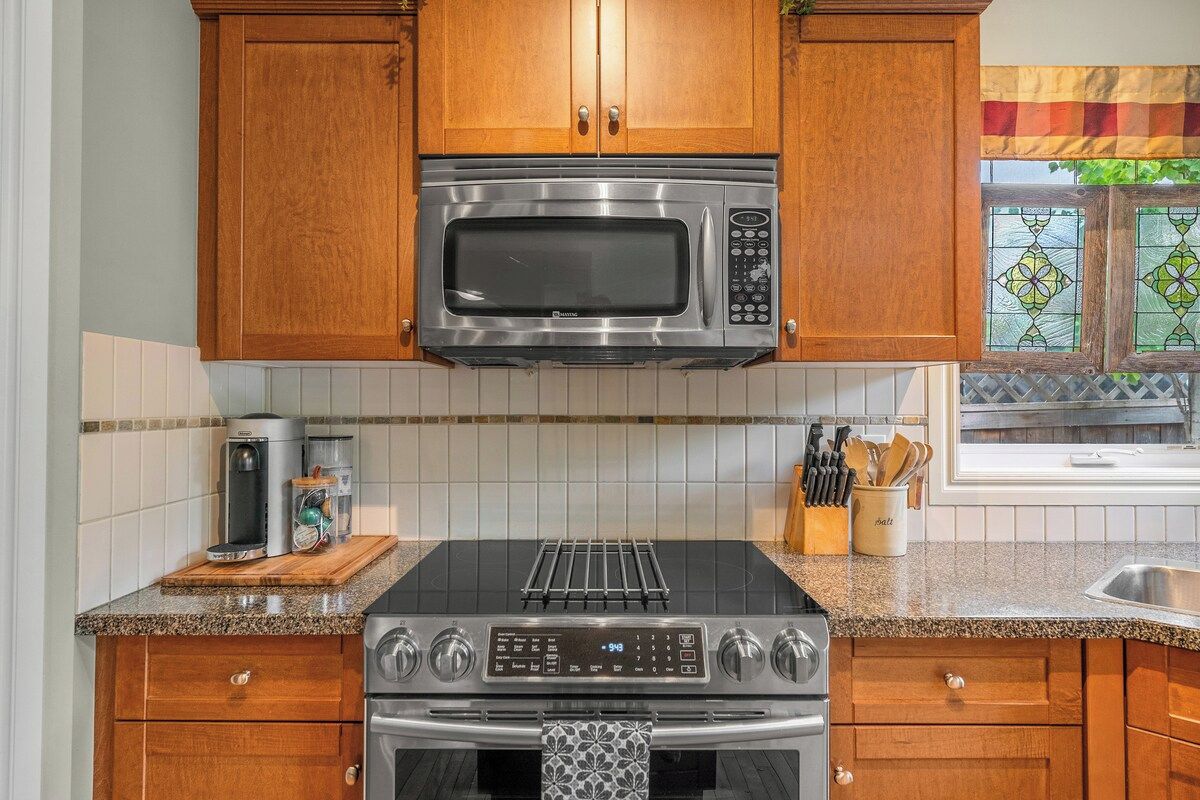 A kitchen with wooden cabinets, a stainless steel microwave, a gas stove, and a coffee maker.
