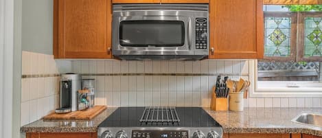 A kitchen with wooden cabinets, a stainless steel microwave, a gas stove, and a coffee maker.