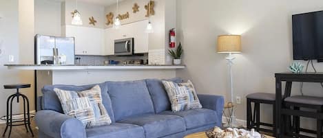 A modern living space with a sofa, a coffee table, a kitchen area, and a dining table.