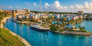 A marina with a large yacht docked, surrounded by colorful buildings and a clear blue sky. - Bahamian Adventure at Harborside Resort at Atlantis + Resort Waterpark Amenities (Nassau)