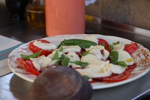 A plate of food with tomatoes, cheese, and basil. - Room 'Chambre Pavlova' with Wi-Fi and Air Conditioning (Aigues-Mortes)