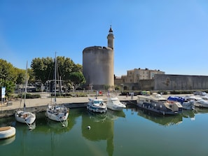 Un port amb vaixells amarrats, una torre destacada i un edifici amb torre.