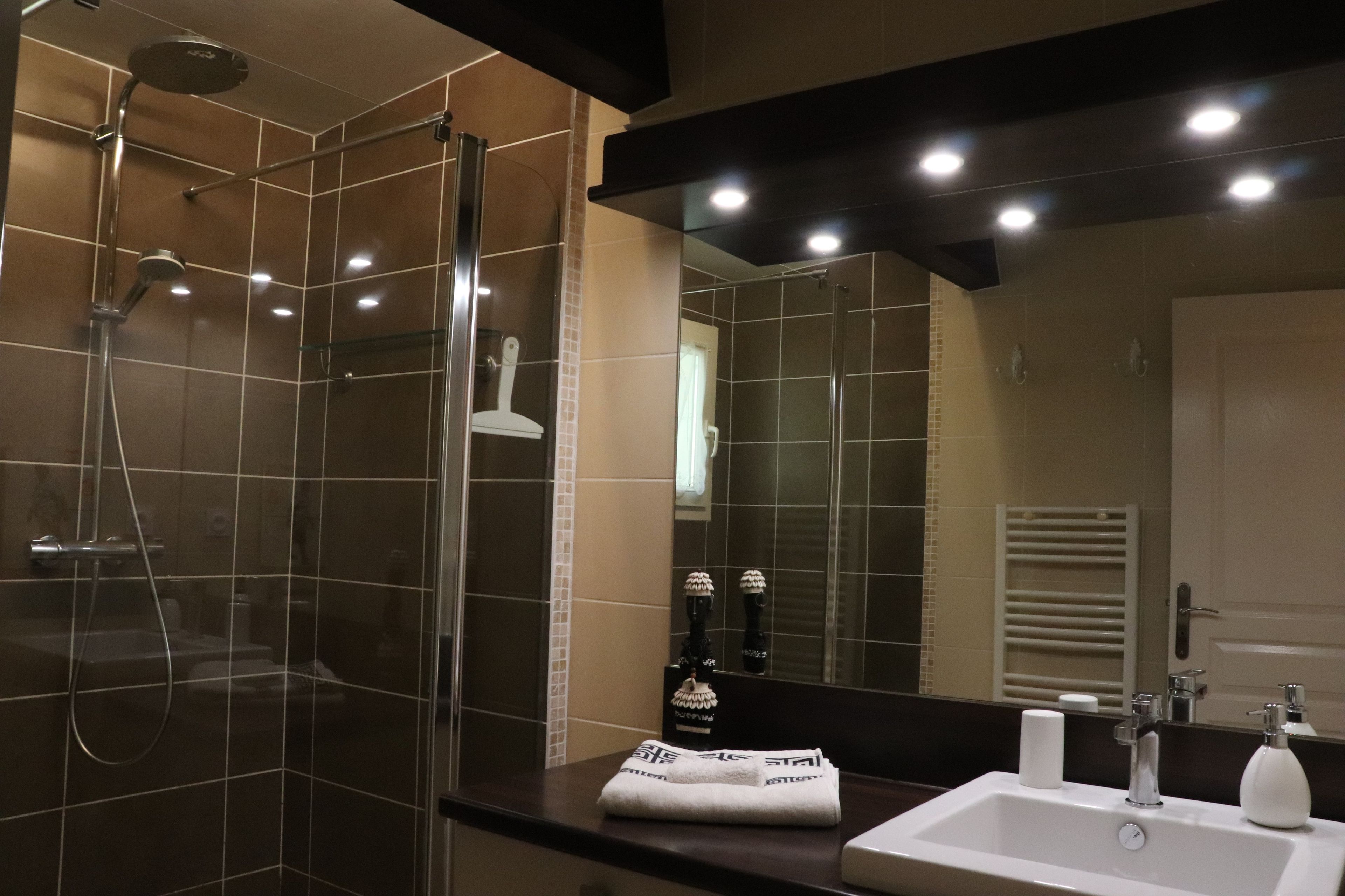 Un bagno moderno con cabina doccia in vetro, lavandino bianco e un ampio specchio.