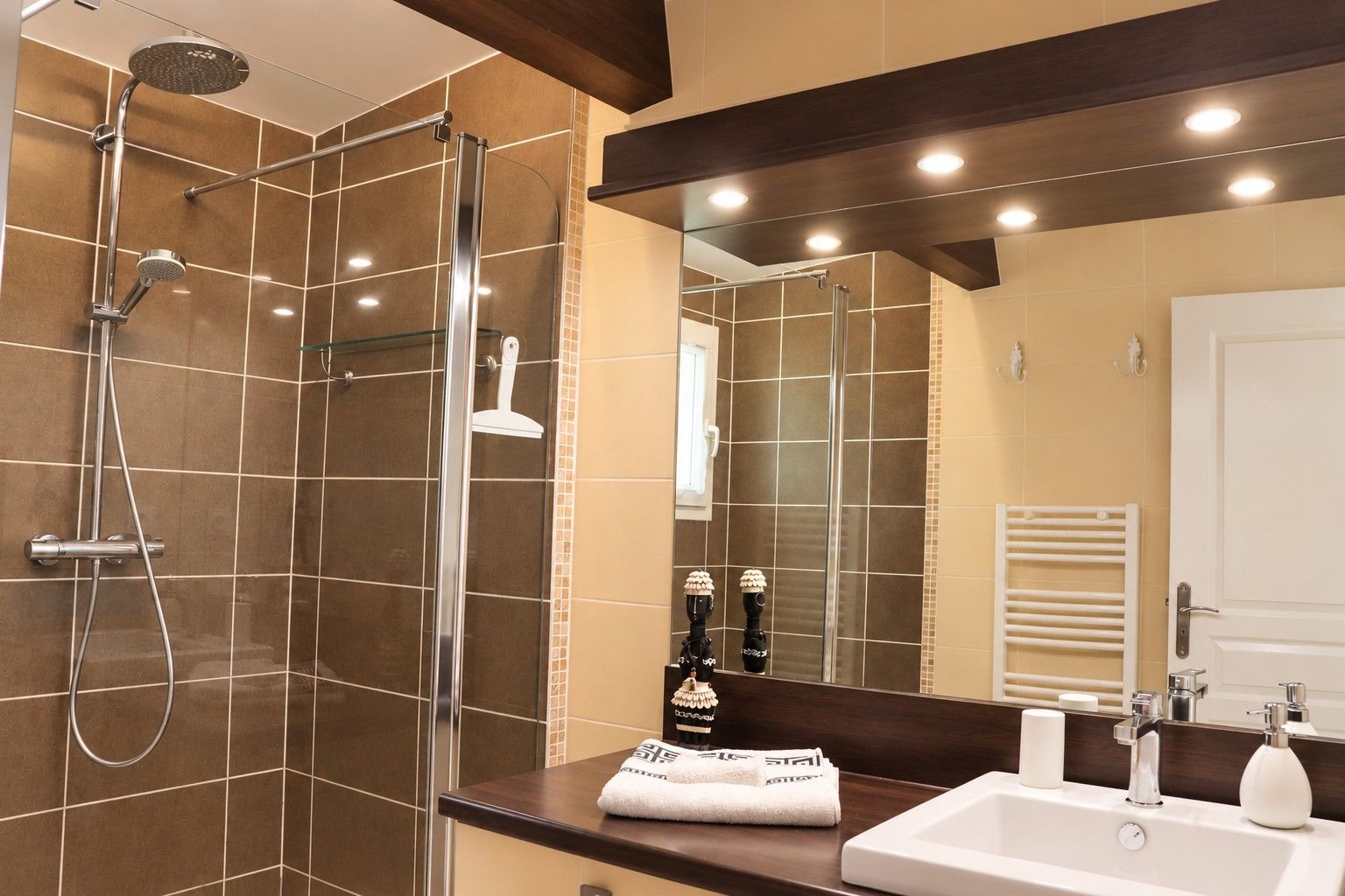 Un bagno moderno con cabina doccia in vetro, uno specchio grande e un lavandino con articoli da toilette.