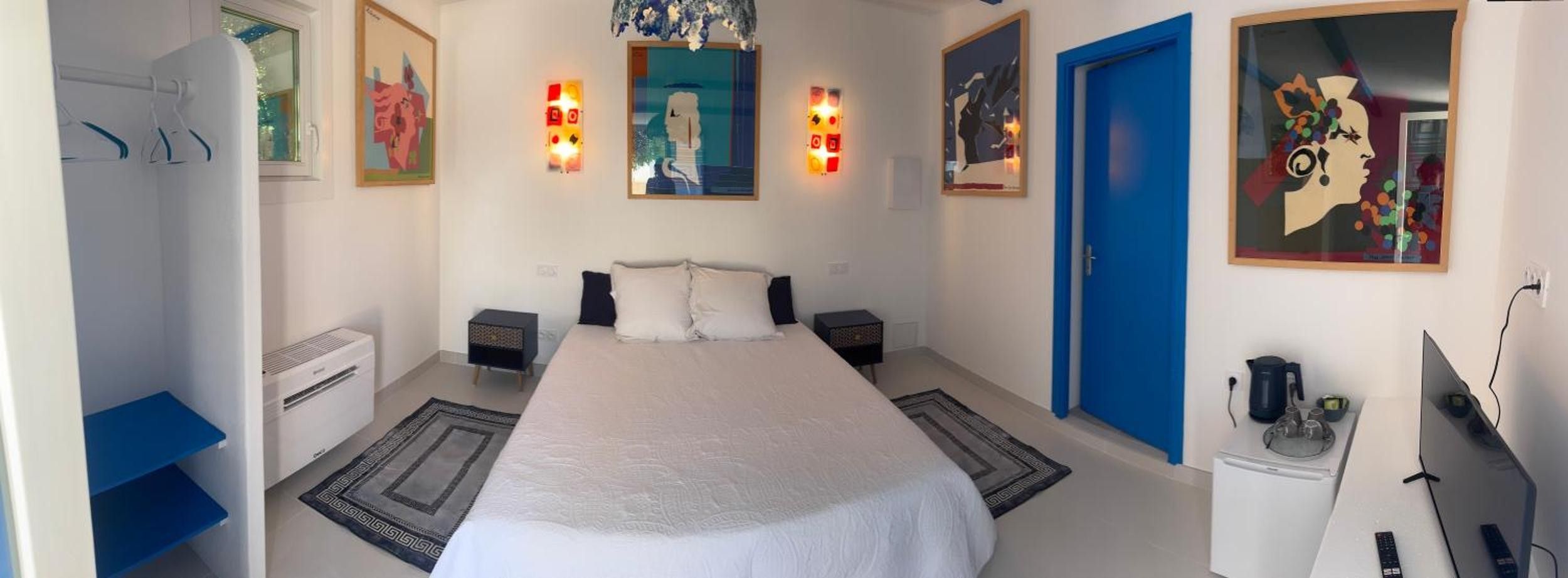 Una camera da letto con un letto, comodini, un armadio e opere d'arte alle pareti.