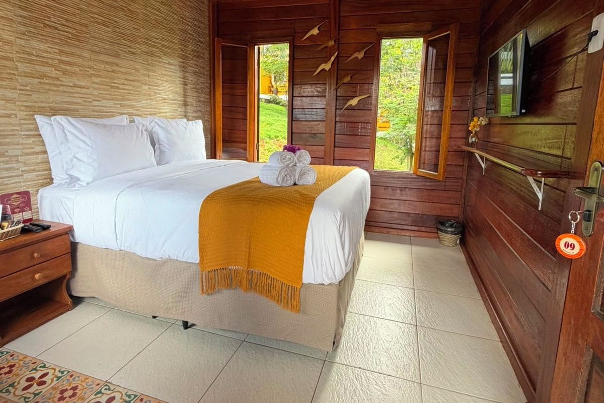 A bedroom with a bed, bedside table, and a hanging light fixture.