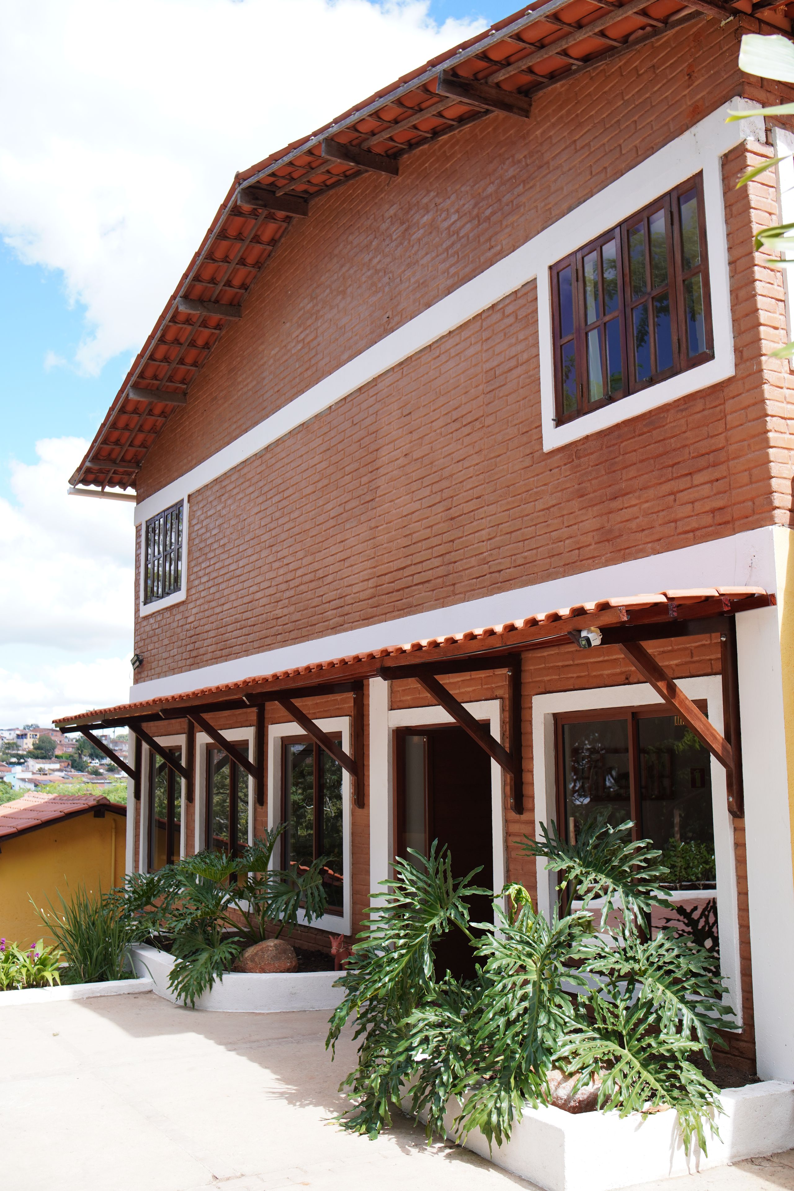 Una casa de dos pisos con techo de tejas y un balcón.