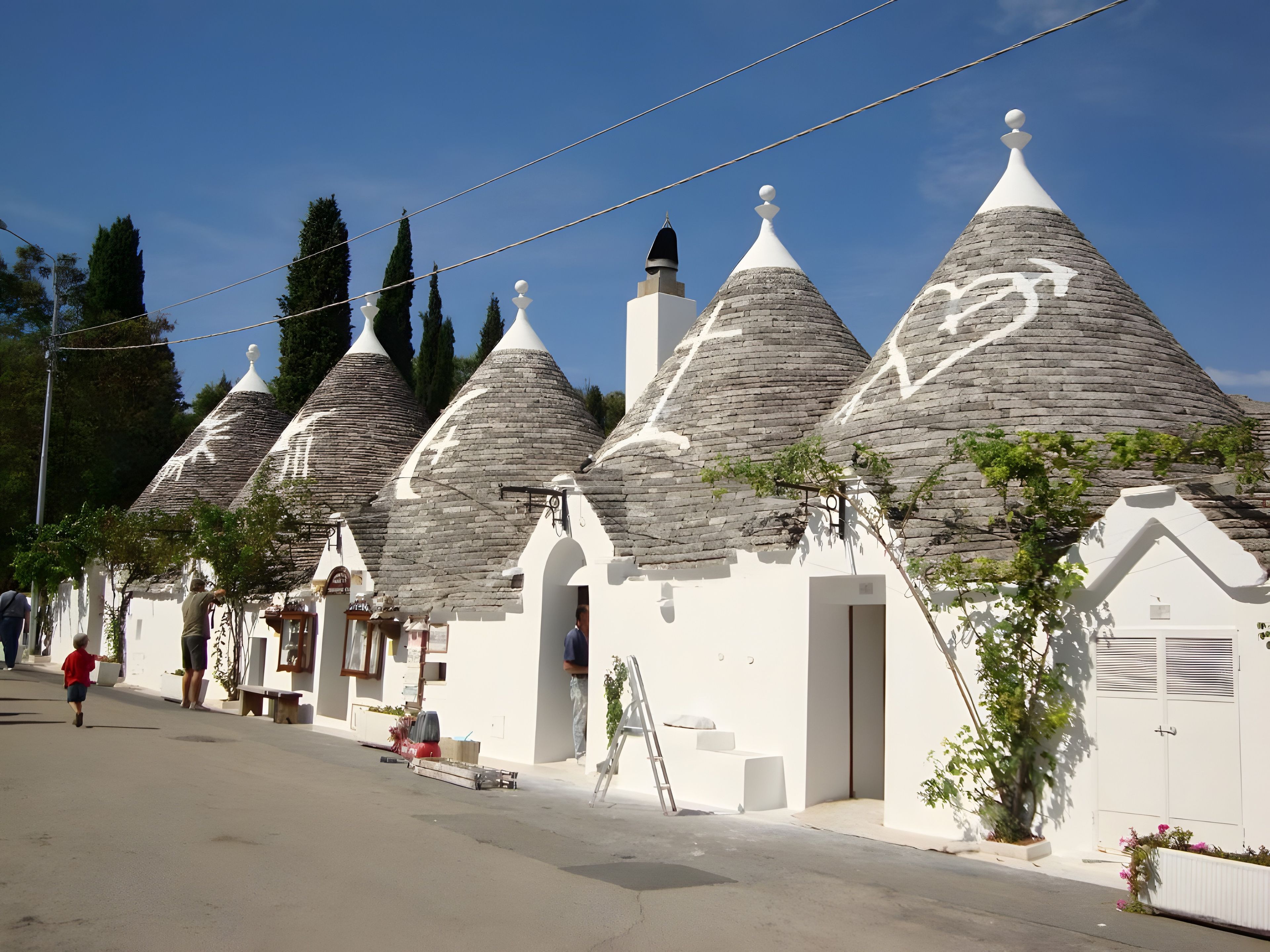 Una fila di edifici tradizionali con tetti in pietra e pareti bianche, sotto un cielo sereno.