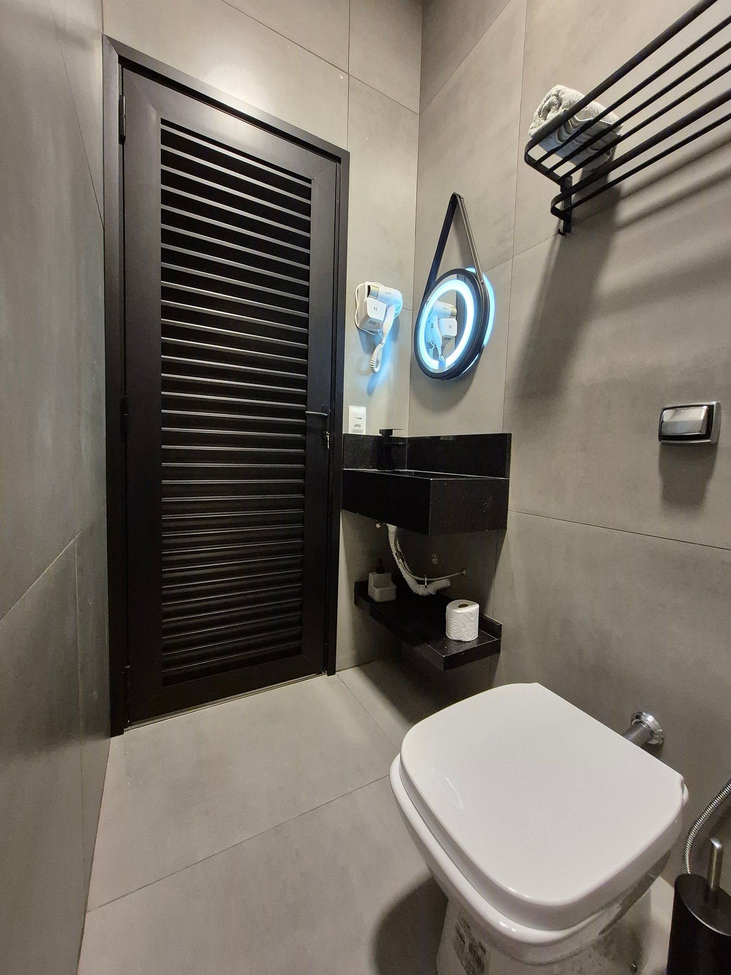 Ein modernes Badezimmer mit Toilette, Handtuchhalter und einem an der Wand befestigten Telefon.
