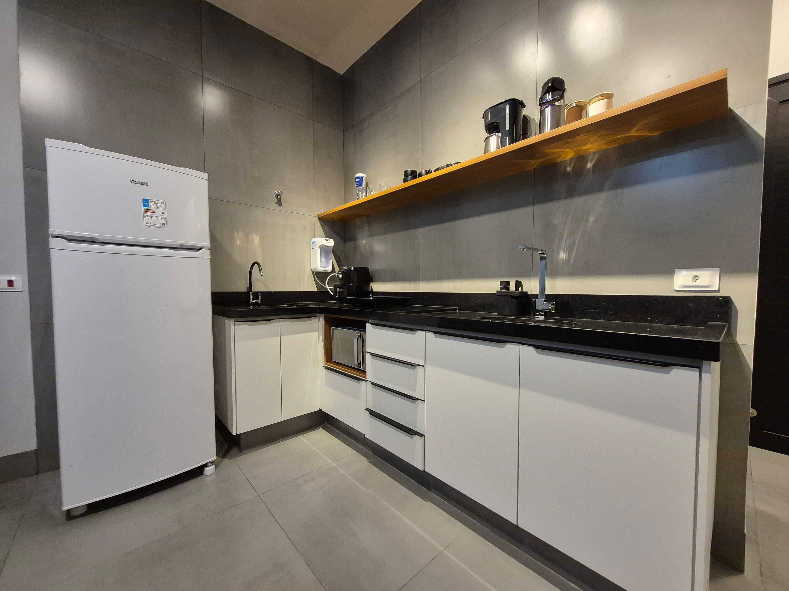 A modern kitchen with a built-in refrigerator, a coffee maker, and a shelf with kitchenware.