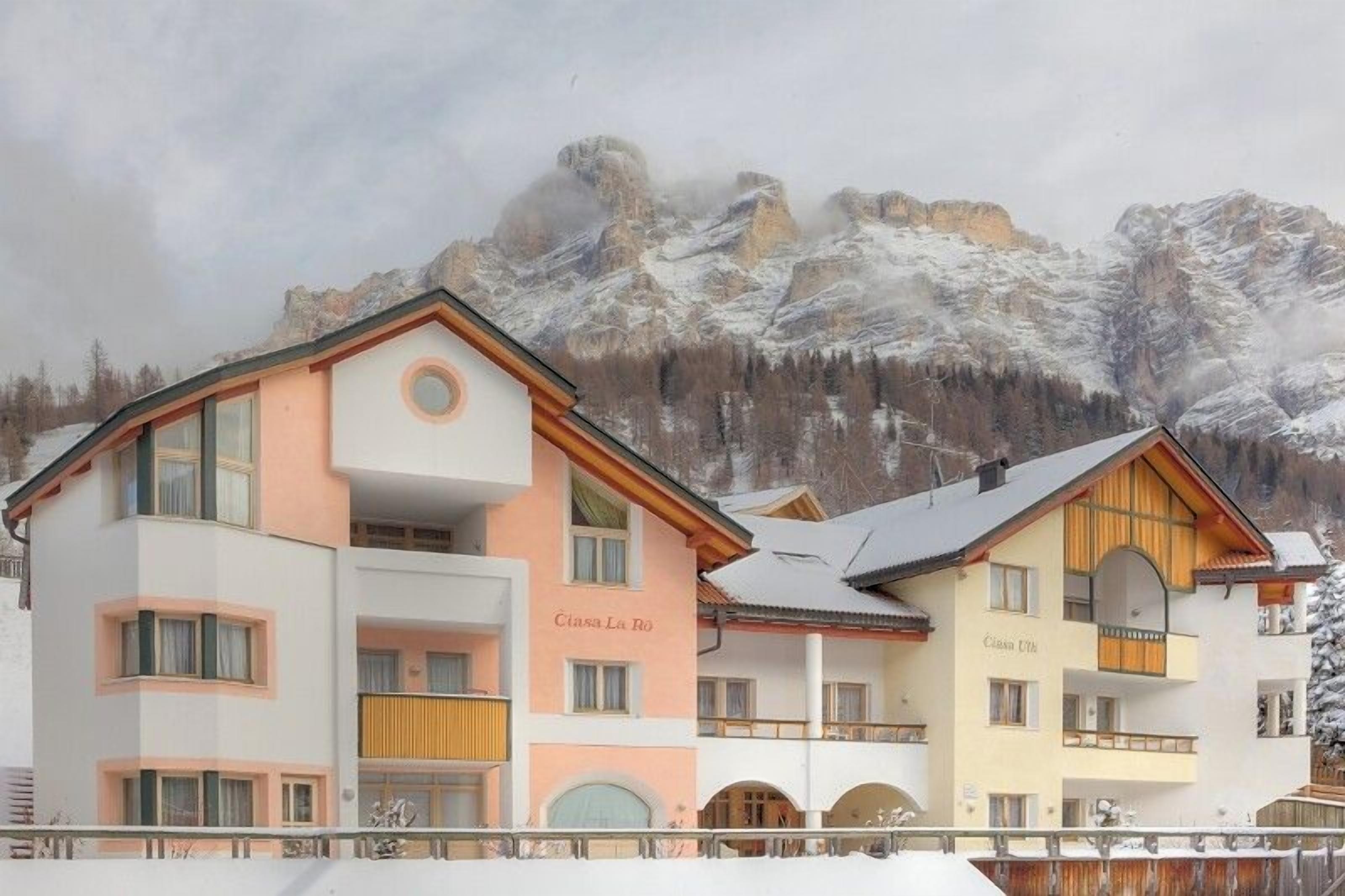 A multi-story hotel with balconies and a mountainous backdrop.